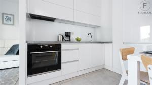 a kitchen with white cabinets and a black oven at City Center SPA Apartments Pool & Parking in Gdańsk