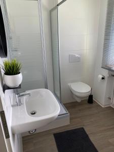 a white bathroom with a sink and a toilet at Apartmenthaus Selbitz in Selbitz