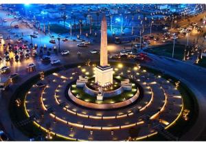 a large monument with lights in a city at night at Panorama New City in Cairo