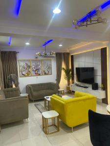 a living room with a yellow couch and a tv at Apartment by Grace wheel in Abeokuta