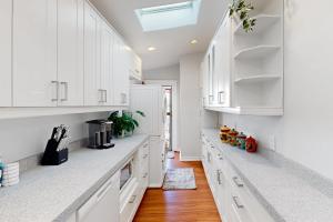 una cucina bianca con armadi bianchi e pavimenti in legno di Madison Cottage a San Diego