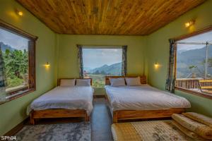 two beds in a room with two windows at Stone Paradise Homestay in Sa Pa