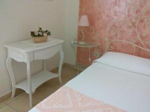 una camera con un letto e un tavolo bianco con una pianta di B&B da Anna a Bosa