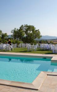 einen Pool mit weißen Stühlen, einem Tisch und einer Person in der Unterkunft Agriturismo Il Tiro in Castel del Piano