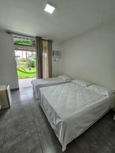 a bedroom with two beds and a large window at Capri Hotel in São Francisco do Sul