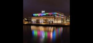 Modern Dublin City Centre في دبلن: مبنى به أضواء ملونة على المياه في الليل