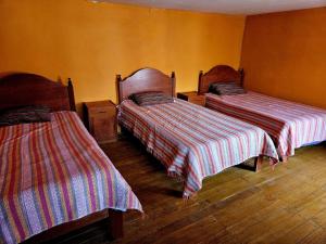 two beds in a room with yellow walls at KanchayKillaWasi in Chinchero