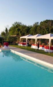 ein Pool mit Tischen und weißen Sonnenschirmen neben in der Unterkunft Agriturismo Il Tiro in Castel del Piano