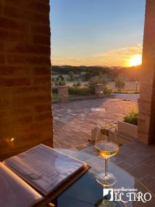 a glass of wine sitting on a table with the sunset at Agriturismo Il Tiro in Castel del Piano