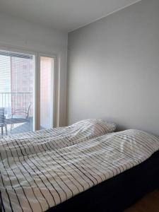 ein Bett in einem Schlafzimmer mit einem großen Fenster in der Unterkunft Uusi korkea tasoinen kaksio, ilmastointi in Turku