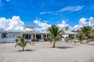una casa bianca sulla spiaggia con palme di White Sands Beach House a Maya Beach