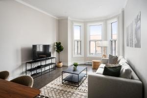 Plateau Prime Residence في مونتريال: غرفة معيشة مع أريكة وتلفزيون