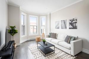 Plateau Prime Residence في مونتريال: غرفة معيشة مع أريكة بيضاء وطاولة