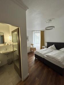 a bedroom with a bed and a bathroom with a sink at Landhaus Hotel Neuss in Neuss