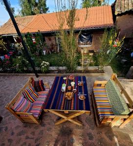 an outdoor table with two chairs and a table with plates at KanchayKillaWasi in Chinchero