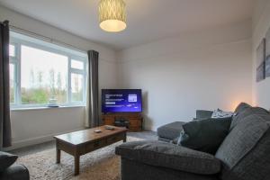 a living room with a couch and a tv at Fairways View - Spacious Apartment - Sleeps 6 - Lovely Views in Hoylake