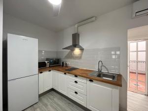 eine weiße Küche mit einer Spüle und einem Kühlschrank in der Unterkunft Ataraxia Casa Vacacional in Mijas