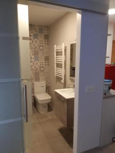 La salle de bains est pourvue de toilettes, d'un lavabo et d'un miroir. dans l'établissement Acogedor apartamento nuevo en Puebla de Lillo, à Puebla de Lillo