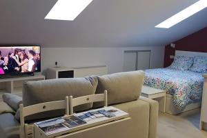 - un salon avec un canapé, un lit et une télévision dans l'établissement Acogedor apartamento nuevo en Puebla de Lillo, à Puebla de Lillo