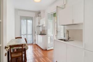 une cuisine avec des placards blancs et une table avec des chaises dans l'établissement Casa Gallo, à Alassio