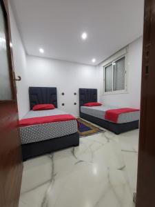 マラケシュにあるMagnifique appartement duplex à 5min de l'aéroport de Marrakechの大理石フロアの客室で、ベッド2台が備わります。