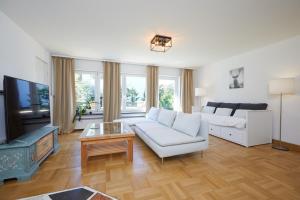 a living room with a white couch and a tv at Ferienwohnung zum Hirschgarten in Krün +19 photos
