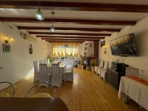 a dining room with a table and white chairs and a television at Casa Edan Breaza in Breaza