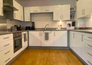 a kitchen with white cabinets and a wooden floor at Amazing 2 Bedroom Apartment At UES in New York