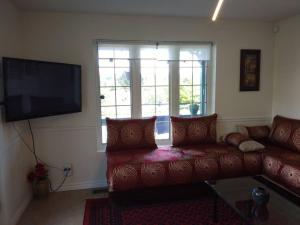ein Wohnzimmer mit einem roten Sofa und einem Flachbild-TV in der Unterkunft Guest house with Moroccan style in Gatineau 15 min from heart of Ottawa in Gatineau