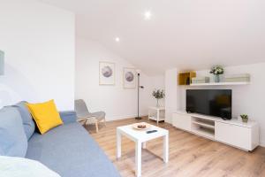 sala de estar con sofá azul y TV en INSIDEHOME Apartments - La Casita de Irene en Palencia