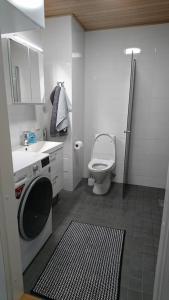 a bathroom with a toilet and a sink and a washing machine at Studio Kakolanmäellä in Turku