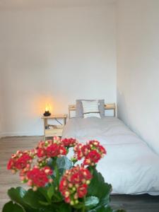 a bedroom with a bed with a vase of red flowers at Appartement Ostend in Ostend