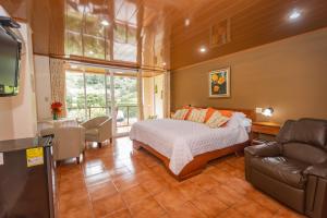 um quarto com uma cama, um sofá e uma televisão em El Oasis Hotel y Restaurante em Boquete