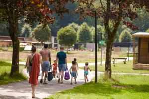 un grupo de personas caminando por una acera en un parque en Camping Le Florenville en Florenville