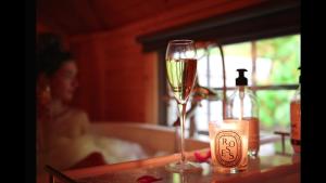 ein Glas Wein auf einem Tisch mit einer Frau in einer Badewanne in der Unterkunft Aos Sí Lodges in Ballachulish