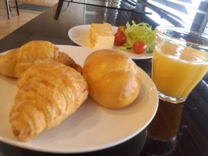 a plate of food with croissants and a glass of orange juice at APA Hotel Miyazaki Miyakonojo Ekimae in Miyakonozyō