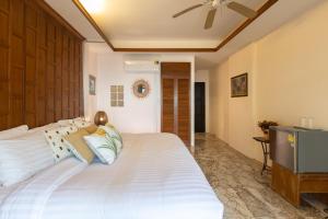 Baansook Resort Koh Chang في كو تشانغ: غرفة نوم مع سرير أبيض كبير مع مروحة سقف