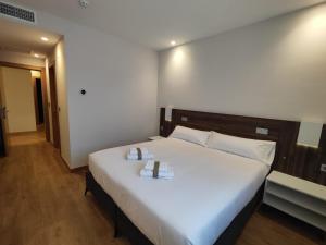 um quarto com uma grande cama branca com dois livros em INSIDEHOME Ciudad de Palencia em Palencia