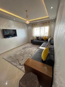 uma sala de estar com um sofá e uma televisão em Luxury Center Town Apartment em Kenitra