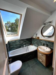 W łazience znajduje się wanna, umywalka i lustro. w obiekcie Loft in Historischer Schmiede w Berlinie