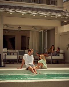 una familia sentada en el borde de una piscina en Apes Hill Barbados Golf and Resort Community, en Saint James