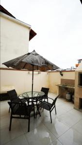 ein Tisch und Stühle mit einem Sonnenschirm auf einer Terrasse in der Unterkunft Residencial Beija Flor Apartamento 23 in Bombinhas