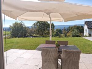 einen Tisch und Stühle unter einem Sonnenschirm auf einer Terrasse in der Unterkunft Ferienwohnung Schwarzwald-Alpenblick in Lenzkirch