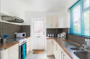 a kitchen with white cabinets and a sink at Central City Castle Apartment with FREE parking in Nottingham