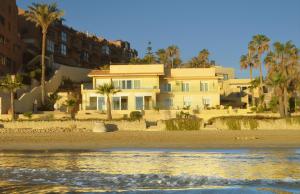 una casa en la playa con palmeras y agua en Excepcional Apartamento LOFT a pie de playa en CHALET ROQUETES, en Alicante