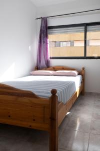 a wooden bed in a room with a window at 3 bdr cozy apt in Condominio Mi, Palmarejo Grande in Praia