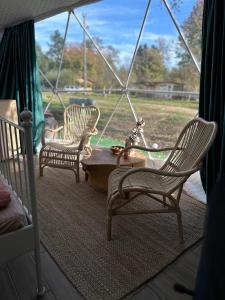 Duas cadeiras e uma mesa num quarto com uma janela em The Frog Glamping em Horezu