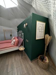 1 dormitorio con cama y pared verde en The Frog Glamping, en Horezu