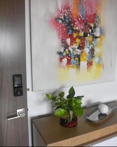 a painting on a wall above a table with a plant at Casa Las Minas en Pilón in Colón