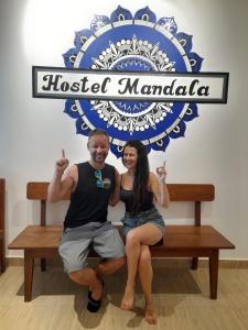 a man and woman sitting on a bench under a sign at Hostel Mandala in Anjuna